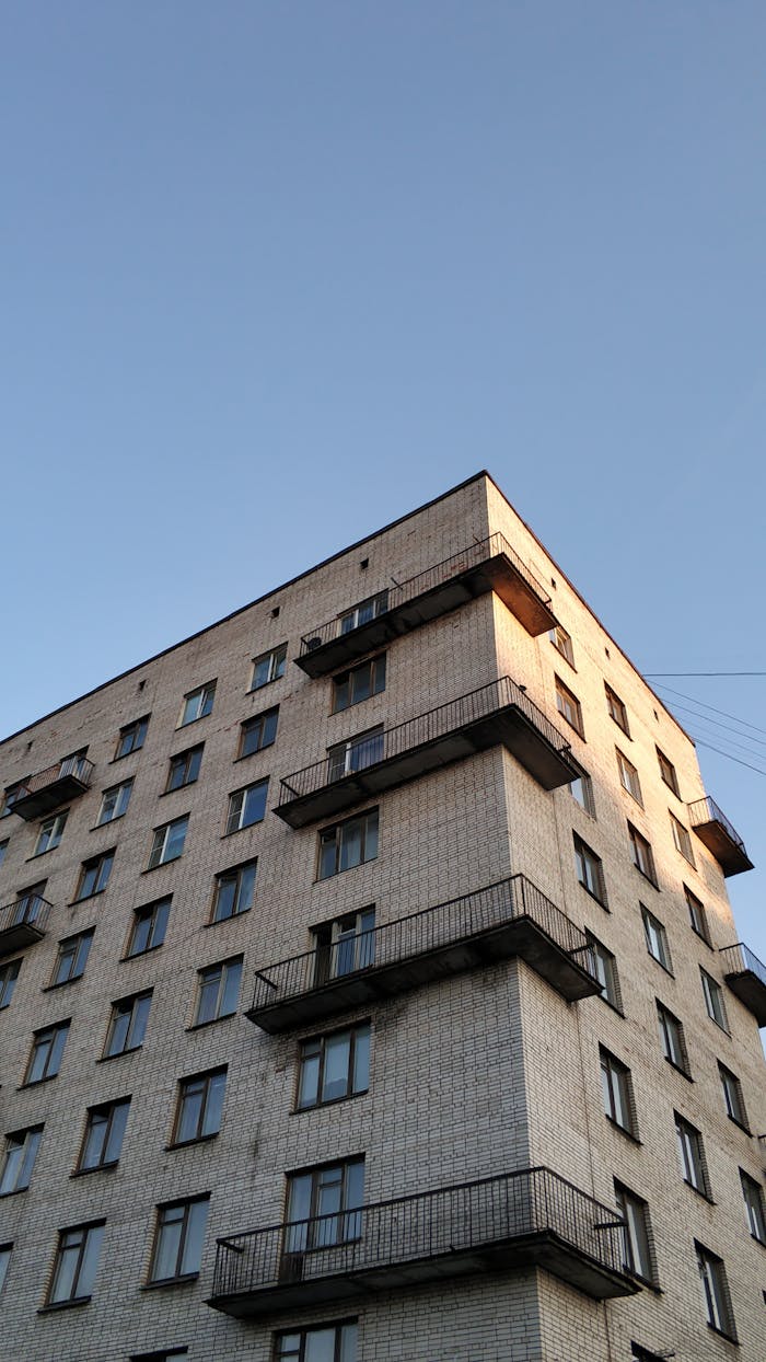 Services Low angle view of a brick apartment building in Sankt-Peterburg under a clear blue sky.